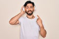 Young handsome hispanic man wearing headphones listening to music over isolated background very happy pointing with hand and Royalty Free Stock Photo