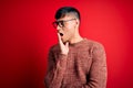 Young handsome hispanic man wearing nerd glasses over red background bored yawning tired covering mouth with hand Royalty Free Stock Photo