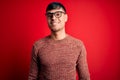 Young handsome hispanic man wearing nerd glasses over red background with a happy and cool smile on face Royalty Free Stock Photo