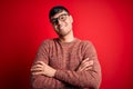 Young handsome hispanic man wearing nerd glasses over red background happy face smiling with crossed arms looking at the camera Royalty Free Stock Photo