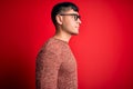 Young handsome hispanic man wearing nerd glasses over red background looking to side, relax profile pose with natural face and Royalty Free Stock Photo