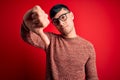 Young handsome hispanic man wearing nerd glasses over red background looking unhappy and angry showing rejection and negative with Royalty Free Stock Photo