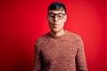 Young handsome hispanic man wearing nerd glasses over red background making fish face with lips, crazy and comical gesture Royalty Free Stock Photo