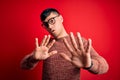 Young handsome hispanic man wearing nerd glasses over red background Moving away hands palms showing refusal and denial with Royalty Free Stock Photo