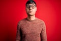 Young handsome hispanic man wearing nerd glasses over red background puffing cheeks with funny face Royalty Free Stock Photo