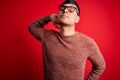 Young handsome hispanic man wearing nerd glasses over red background Suffering of neck ache injury, touching neck with hand, Royalty Free Stock Photo