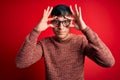 Young handsome hispanic man wearing nerd glasses over red background Trying to open eyes with fingers, sleepy and tired for