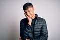 Young handsome hispanic man wearing winter coat standing over white isolated background thinking looking tired and bored with Royalty Free Stock Photo