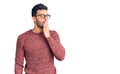 Young handsome hispanic man wearing winter sweater and glasses bored yawning tired covering mouth with hand Royalty Free Stock Photo