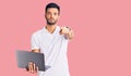 Young handsome hispanic man working using computer laptop pointing with finger to the camera and to you, confident gesture looking Royalty Free Stock Photo