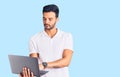 Young handsome hispanic man working using computer laptop thinking attitude and sober expression looking self confident Royalty Free Stock Photo