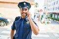 Young handsome hispanic policeman wearing police uniform smiling happy