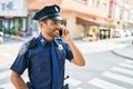 Young handsome hispanic policeman wearing police uniform smiling happy