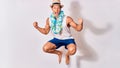 Young handsome hispanic tourist man on vacation wearing summer clothes and hawaiian lei smiling happy Royalty Free Stock Photo