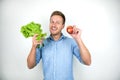 Young handsome holding a whole bunch of salad and fresh red apple smiling on white background