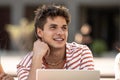 Young handsome hopeful guy smiling.Satisfied teenager sitting with friends smiling and relaxed.