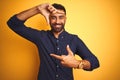 Young handsome indian businessman wearing shirt over isolated yellow background smiling making frame with hands and fingers with Royalty Free Stock Photo