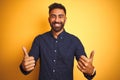 Young handsome indian businessman wearing shirt over isolated yellow background success sign doing positive gesture with hand, Royalty Free Stock Photo