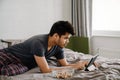 Young handsome indian man liying on bed working with tablet Royalty Free Stock Photo