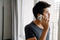 Young handsome indian man talking on phone looking out window Royalty Free Stock Photo