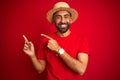 Young handsome indian man wearing t-shirt and hat over isolated red background smiling and looking at the camera pointing with two Royalty Free Stock Photo