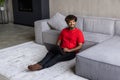 Young indian man working on laptop sittin on floor in living room