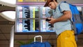 Singapore, 27 may 2018. Young handsome international airport tourist passenger in hat uses mobile phone stands with