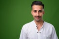 Young handsome Iranian man with mustache against green backgroun