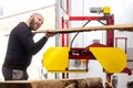 Young handsome joiner man cutting wood board, processing the wood, huge wood cutter or saw, industrial concept Royalty Free Stock Photo