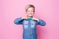 Young handsome kid smiling with blue shirt and butterfly tie. Studio portrait over pink background