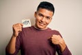 Young handsome latin man celebrating 8th march womens day holding reminder paper with surprise face pointing finger to himself