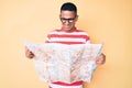 Young handsome latin man holding city map looking positive and happy standing and smiling with a confident smile showing teeth Royalty Free Stock Photo