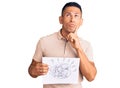 Young handsome latin man holding scribble draw serious face thinking about question with hand on chin, thoughtful about confusing Royalty Free Stock Photo