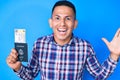 Young handsome latin man holding united states passport and boarding pass celebrating victory with happy smile and winner Royalty Free Stock Photo