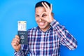 Young handsome latin man holding united states passport and boarding pass smiling happy doing ok sign with hand on eye looking Royalty Free Stock Photo