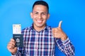 Young handsome latin man holding united states passport and boarding pass smiling happy and positive, thumb up doing excellent and Royalty Free Stock Photo