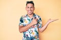 Young handsome latin man wearing summer clothes amazed and smiling to the camera while presenting with hand and pointing with Royalty Free Stock Photo