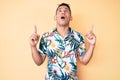 Young handsome latin man wearing summer clothes amazed and surprised looking up and pointing with fingers and raised arms Royalty Free Stock Photo