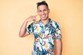 Young handsome latin man wearing summer clothes smiling doing phone gesture with hand and fingers like talking on the telephone Royalty Free Stock Photo