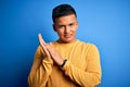 Young handsome latin man wearing yellow casual sweater over isolated blue background clapping and applauding happy and joyful, Royalty Free Stock Photo