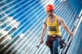 Young handsome macho man builder with muscular athletic strong body in orange hard hat or helmet holds wrench near wood ladde Royalty Free Stock Photo