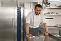 Young handsome male chef cleaning his workplace on kitchen in restaurant Royalty Free Stock Photo