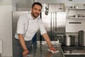 Young handsome male chef cleaning his workplace on kitchen in restaurant Royalty Free Stock Photo