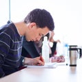 Young, handsome male college student sitting in a classroom full Royalty Free Stock Photo