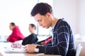 Young, handsome male college student sitting in a classroom full Royalty Free Stock Photo