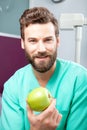 Young handsome male doctor smiling holding green fresh apple Royalty Free Stock Photo