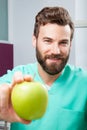 Young handsome male doctor smiling holding green fresh apple Royalty Free Stock Photo