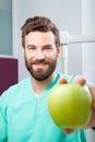 Young handsome male doctor smiling holding green fresh apple Royalty Free Stock Photo