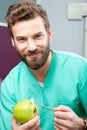 Young handsome male doctor smiling with white teeth holding apple Royalty Free Stock Photo