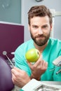 Young handsome male doctor smiling with white teeth holding apple Royalty Free Stock Photo
